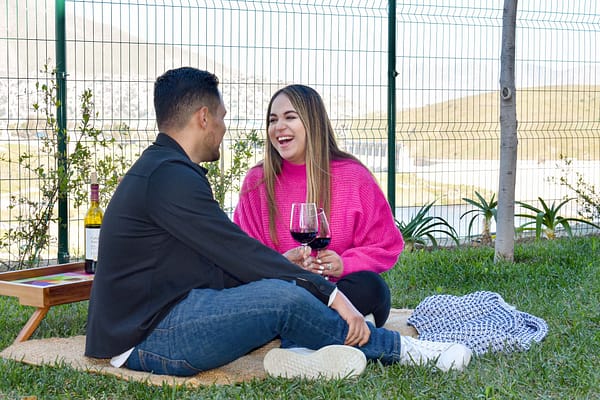 Un hombre y una mujer disfrutando de un momento de relax sobre una manta, bebiendo vino en Privada Cobalto.